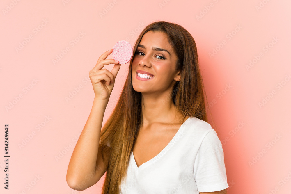 Young caucasian woman cleaning his face with a facial disk isolated Young caucasian woman cleaning his face with a facial disk isolated