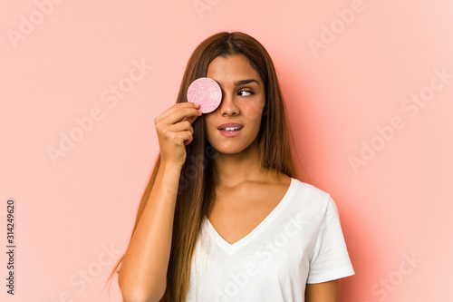 Young caucasian woman cleaning his face with a facial disk isolated