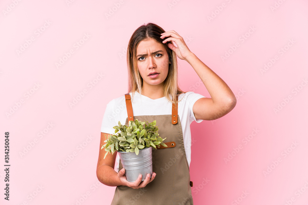 Young caucasian gardener woman in a pink background being shocked, she has remembered important meeting. Young caucasian gardener woman in a pink background being shocked, she has remembered important meeting.
