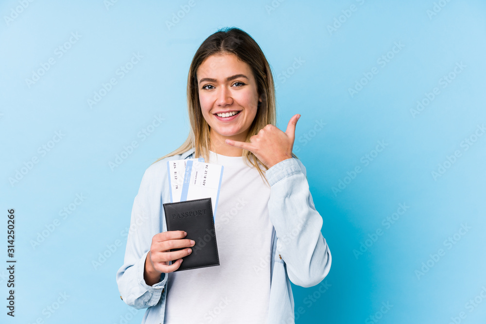 Young caucasian woman holding a passport isolated showing a mobile phone call gesture with fingers. Young caucasian woman holding a passport isolated showing a mobile phone call gesture with fingers.