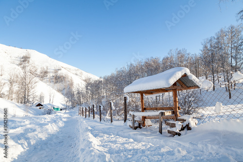 Wallpaper Mural The picturesque landscape with snowdrifts, a hiking trail along the fence with a wooden gazebo in the Altai mountains under a blue sky with snow in winter. Torontodigital.ca