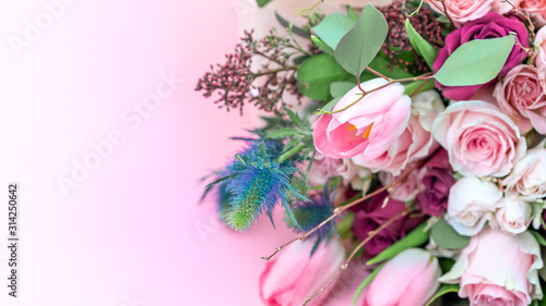 Fototapeta Naklejka Na Ścianę i Meble -  A closeup bouquet of roses and tulips decorated with leaves and twigs of other beautiful plants. Holiday concept. Flowers for Mother's Day. Copy space.