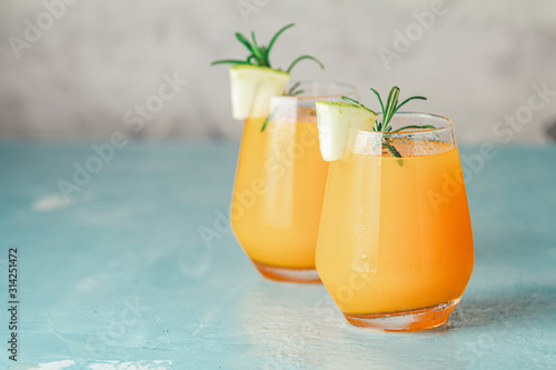 Yellow orange cocktail with melon and mint in glass on blue concrete background, close up. Summer drinks and alcoholic cocktails. Alcoholic or detox cocktail