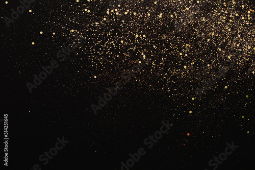 Christmas Gold glitter on black background. Holiday abstract texture