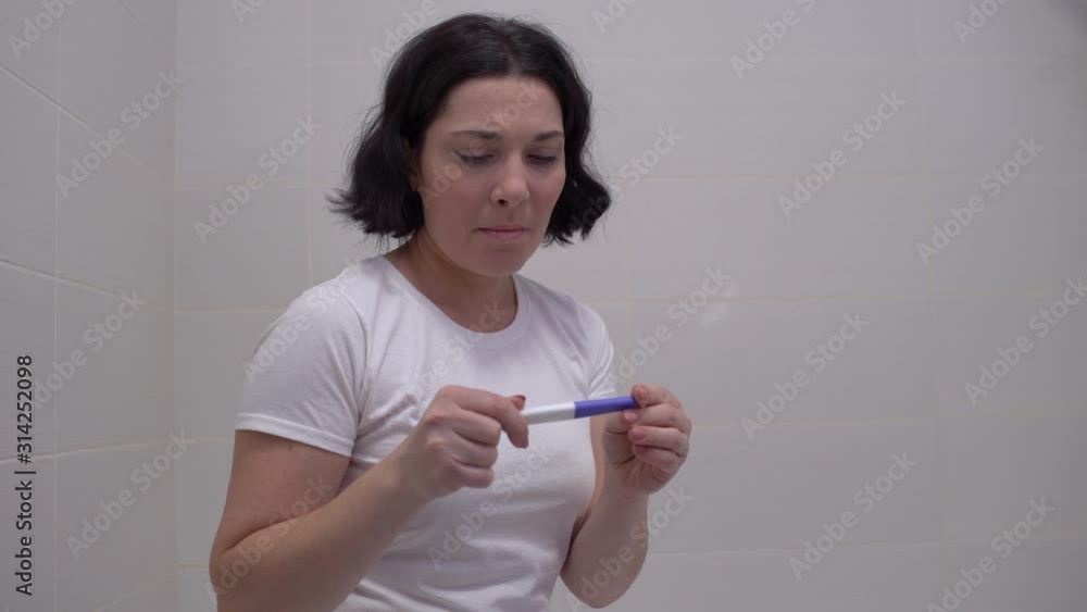 Hopeful woman checking pregnancy test, crying disappointed with negative result Hopeful woman checking pregnancy test, crying disappointed with negative result