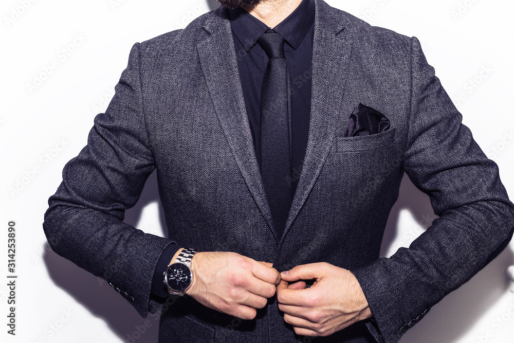 closeup fashion image of luxury watch on wrist of man.body detail of a business man.Man's hand in a grey checkered suit closeup at white background.Not isolated