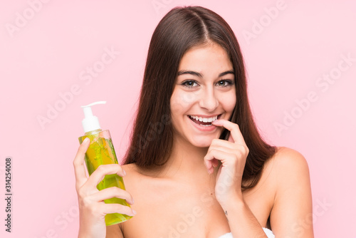 Young caucasian woman holding a moisturizer with aloe vera isolated relaxed thinking about something looking at a copy space.