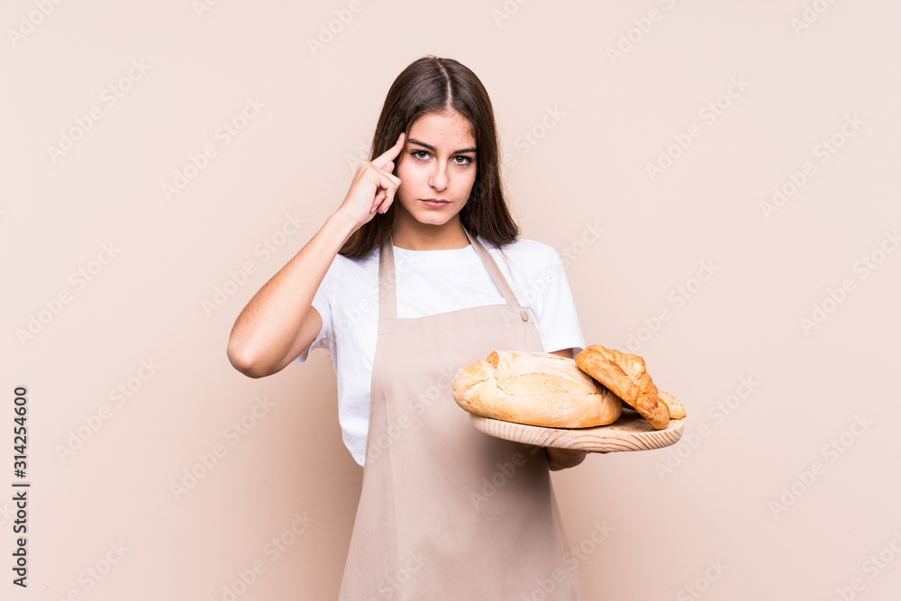 Young caucasian baker woman isolated pointing temple with finger, thinking, focused on a task. Young caucasian baker woman isolated pointing temple with finger, thinking, focused on a task.