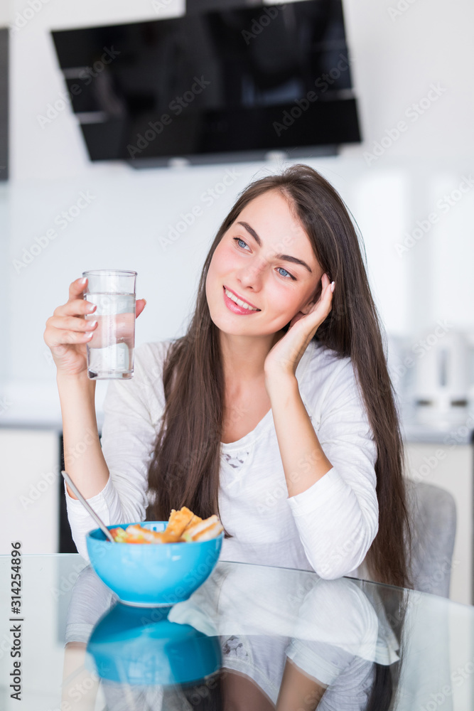 Young woman eating salad and holding a mixed salad in the kitchen Young woman eating salad and holding a mixed salad in the kitchen