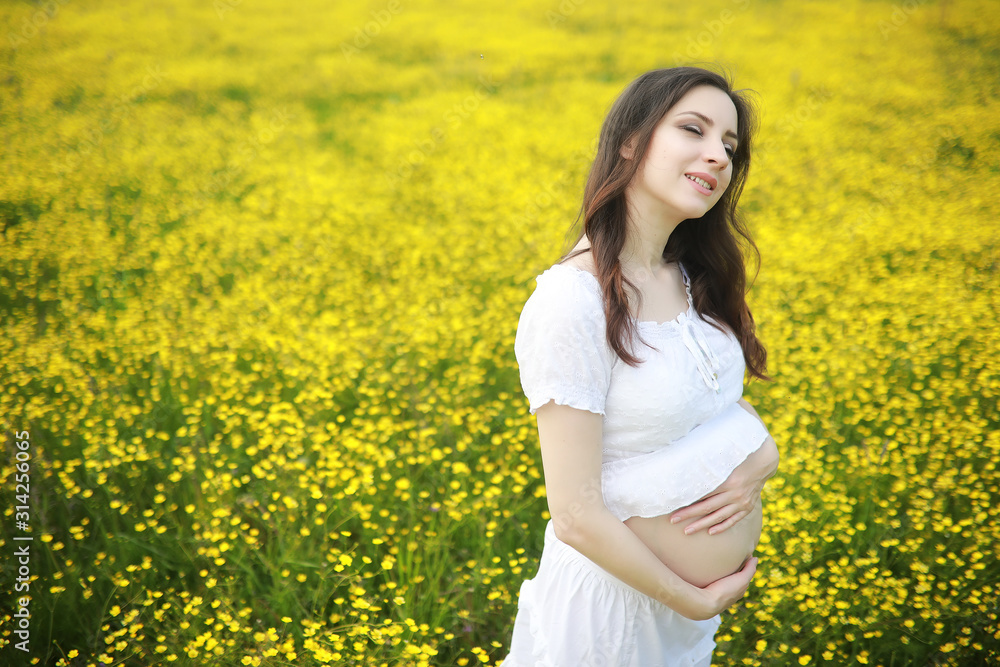 Pregnant woman in a dress in a field of flowers Pregnant woman in a dress in a field of flowers