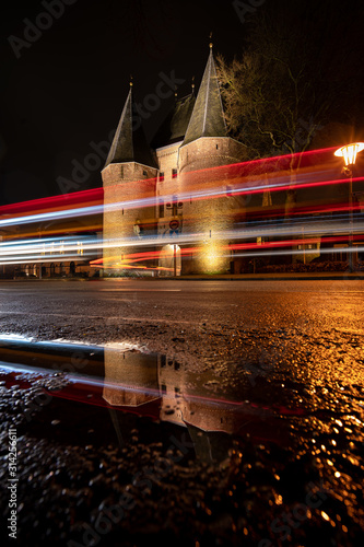 Traffic light trails before monumental city gate during rainy evening photo