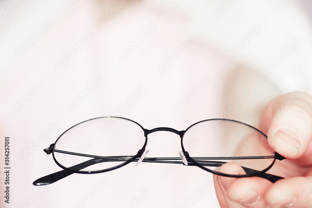 The concept of poor vision. Hold a contact lens and glasses in hand. A poster for advertising glasses and lenses. The concept of poor vision. Hold a contact lens and glasses in hand. A poster for advertising glasses and lenses.