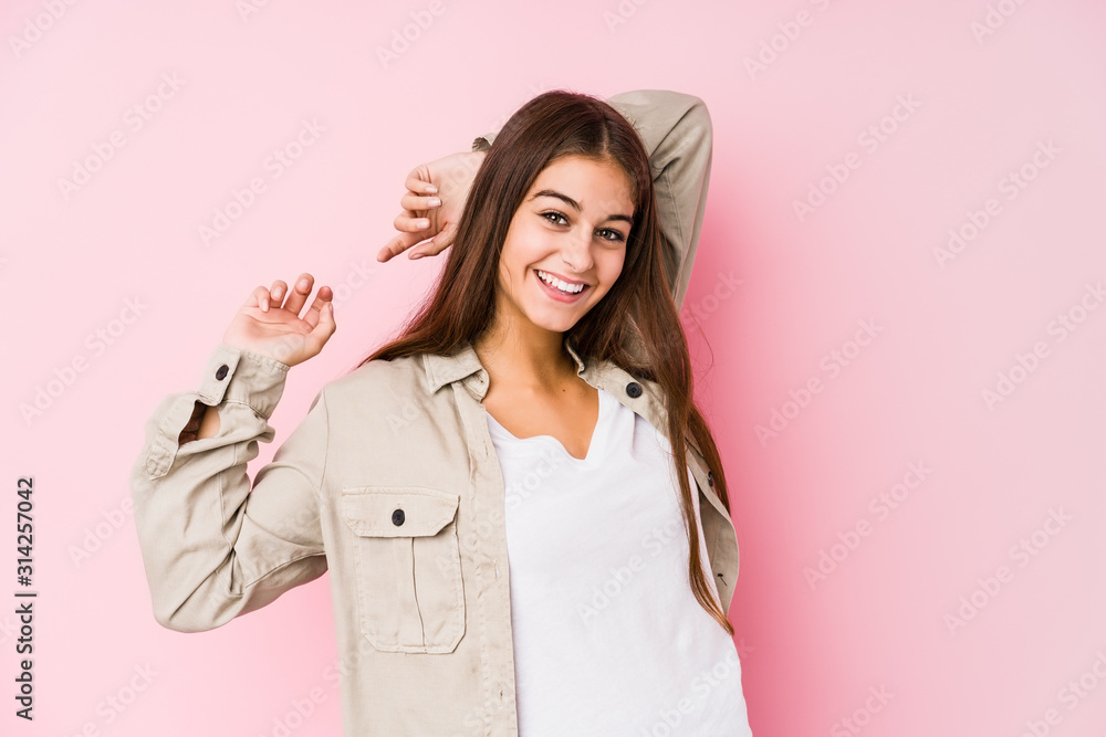 Young caucasian woman posing in a pink background stretching arms, relaxed position. Young caucasian woman posing in a pink background stretching arms, relaxed position.