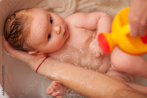 cute newborn baby bathes in the bathroom. The concept of a toddlers ' swimming