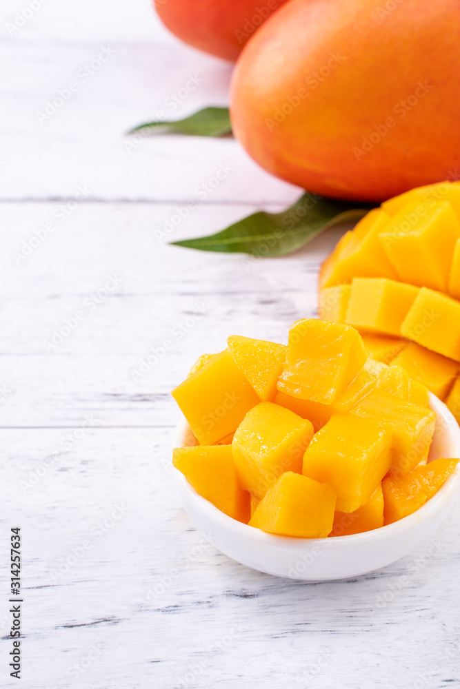 Fresh mango,beautiful chopped fruit with green leaves on bright wooden table background. Tropical fruit design concept, close up, copy space. Fresh mango,beautiful chopped fruit with green leaves on bright wooden table background. Tropical fruit design concept, close up, copy space.