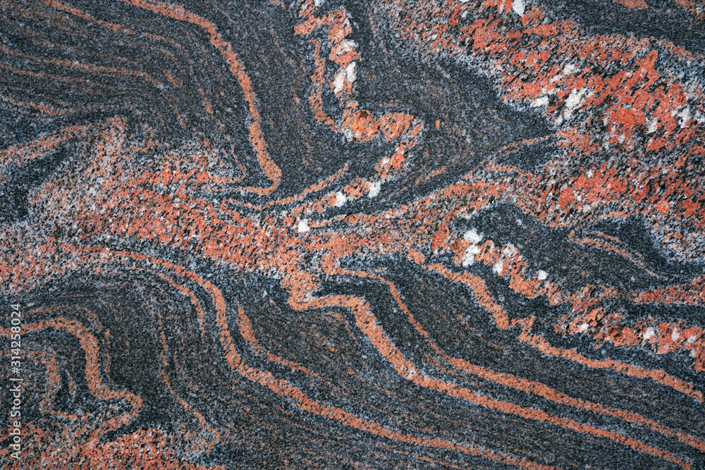 Abstraktes rotes Muster in einer dunklen, glatt geschliffenen Steinplatte