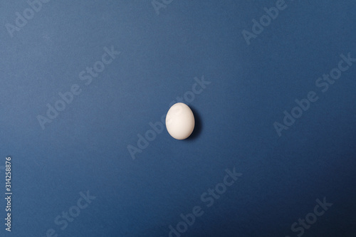 Single white egg on blue background. Holiday concept. Happy Easter