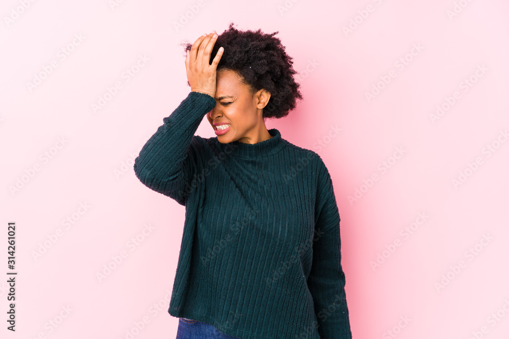 Middle aged african american woman against a pink background isolated forgetting something, slapping forehead with palm and closing eyes. Middle aged african american woman against a pink background isolated forgetting something, slapping forehead with palm and closing eyes.
