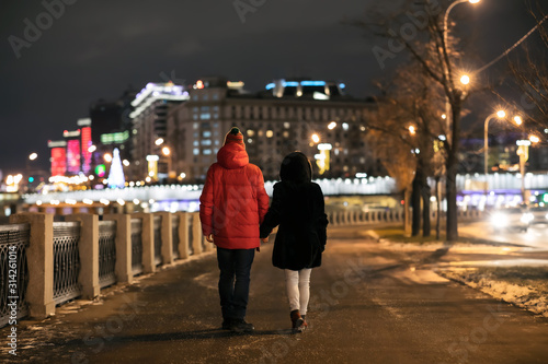 a girl and a guy walking along the embankment of the river