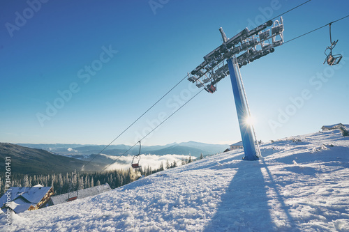 Ski lift with seats going over the mountain and paths from skies and snowboards. Beautiful winter landscape.