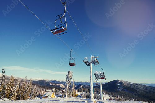Ski lift with seats going over the mountain and paths from skies and snowboards.