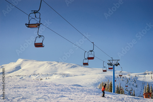 Ski lift with seats going over the mountain and paths from skies and snowboards.