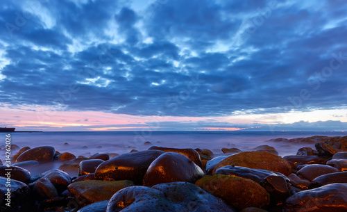 Sea after sunset and beach with big stones.