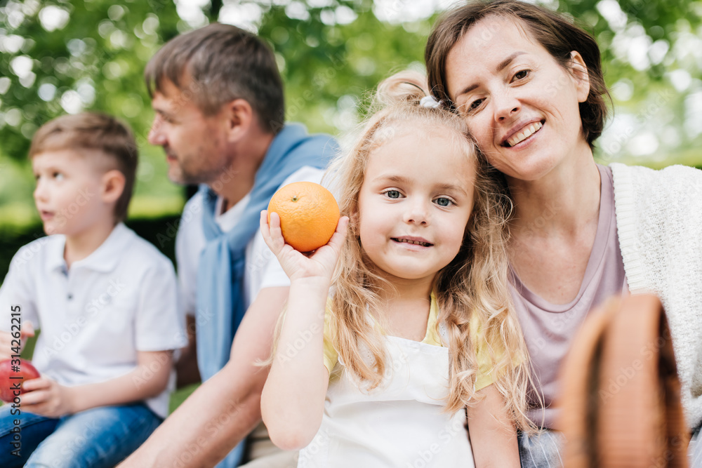 Mother and daughter look at the camera holding an orange. Mother and daughter look at the camera holding an orange.