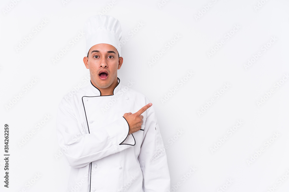 Young latin chef man isolated pointing to the side Young latin chef man isolated pointing to the side