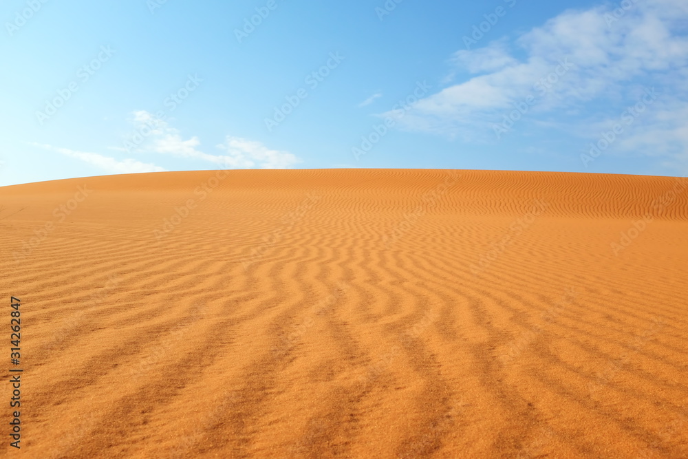 Bright orange desert sand patterns and bright blue sky for a warm summer background