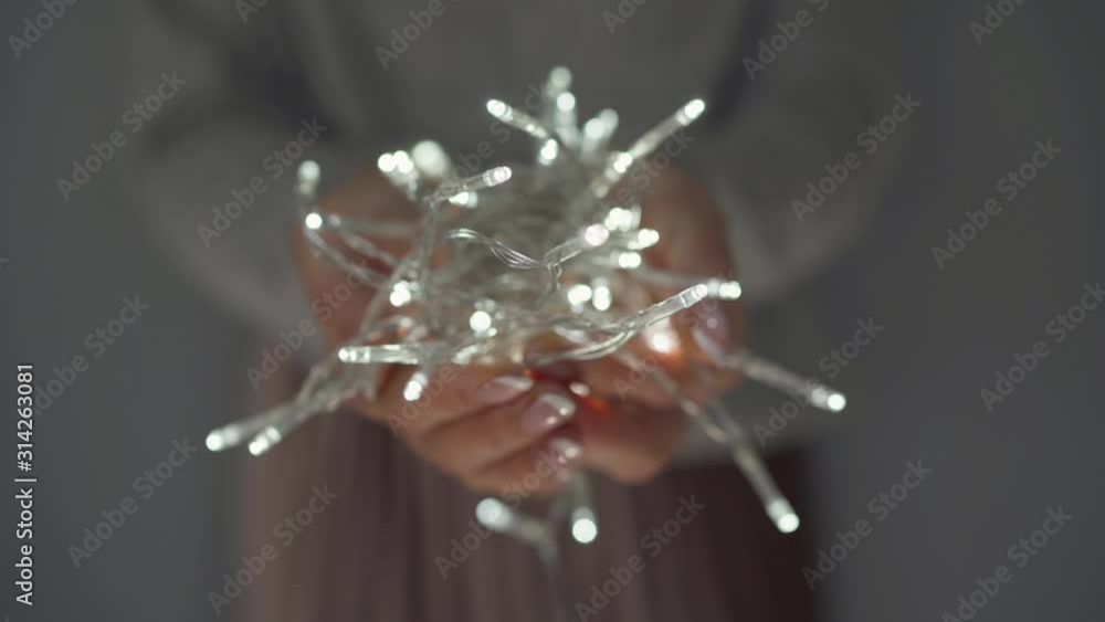 Woman holds white christmas garland in hands close up Woman holds white christmas garland in hands close up