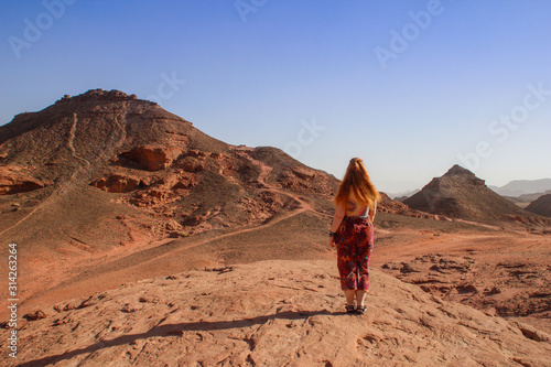 Caucasian woman hippie red-haired traveler with glasses posing against the backdrop of the desert in Timna National Park, Israel,