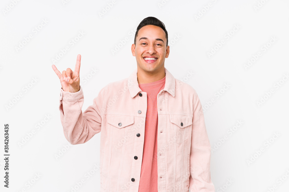 Young latin man posing isolated showing a horns gesture as a revolution concept. Young latin man posing isolated showing a horns gesture as a revolution concept.