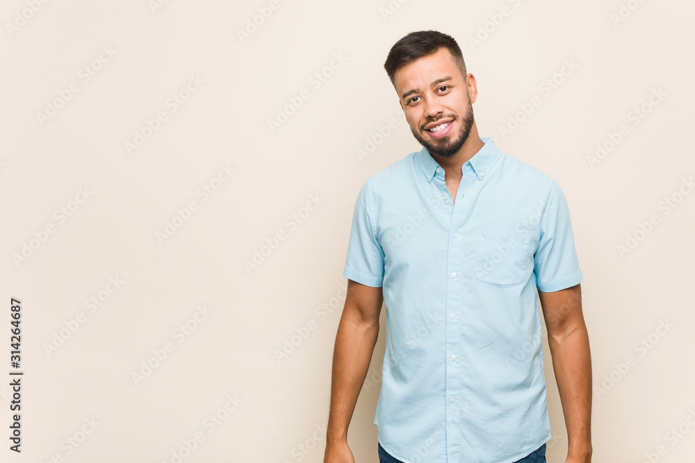 Young south-asian man stretching arms, relaxed position. - obrazy, fototapety, plakaty 