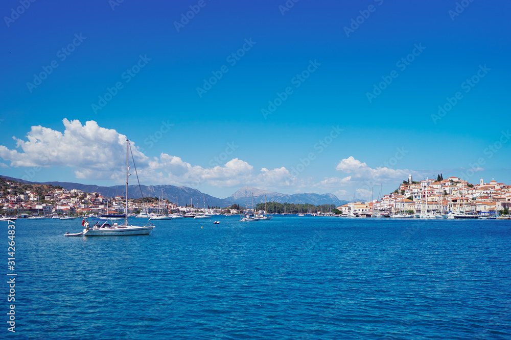 Naklejka premium Scenic view of Poros island in a typical summer day. Old town with traditional white houses near the sea. Saronic gulf, Greece, Europe.