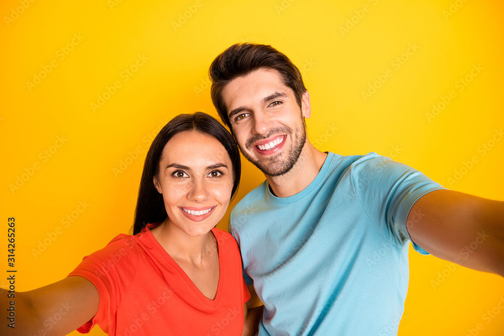 Photo of two funny guy lady people couple making cute selfies recording video for new social network blog wear casual blue orange t-shirts isolated yellow color background Photo of two funny guy lady people couple making cute selfies recording video for new social network blog wear casual blue orange t-shirts isolated yellow color background