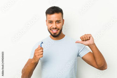 Young south-asian man holding a razor blade feels proud and self confident, example to follow.