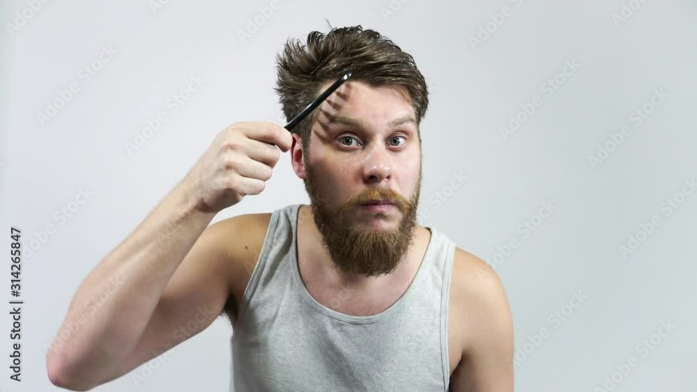 The bearded guy combs her hair and looks in the mirror. The bearded guy combs her hair and looks in the mirror.