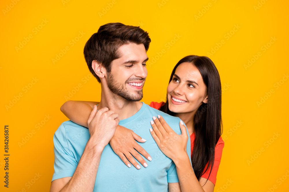 Photo of two adorable guy lady people couple hugging piggyback charming looking eyes hold arms wear casual blue orange t-shirts isolated yellow color background - obrazy, fototapety, plakaty 