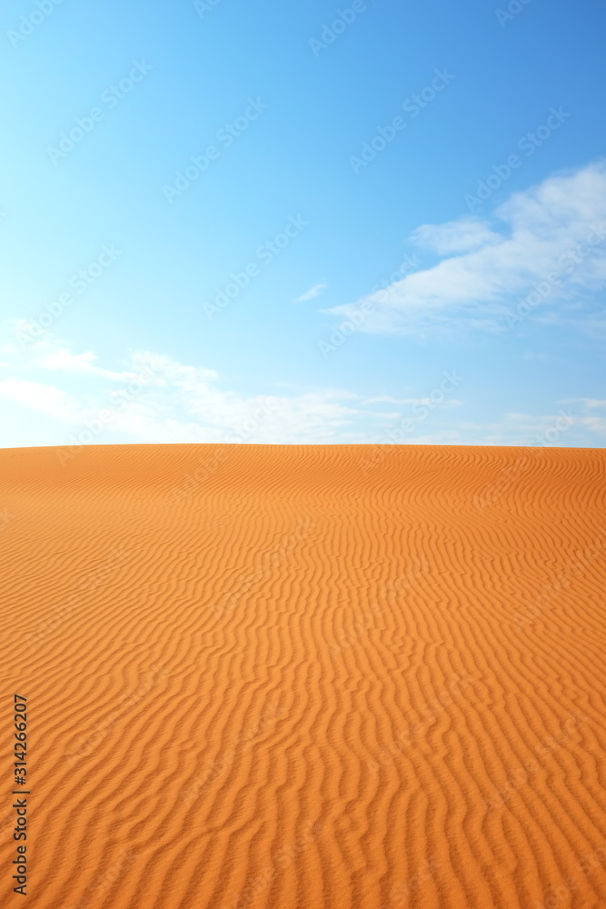 Bright orange desert sand color against a bright blue sky for a hot summer background
