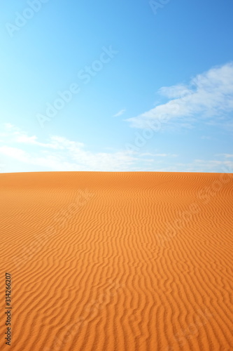 Bright orange desert sand color against a bright blue sky for a hot summer background