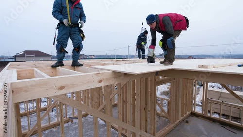 Timelapse zooming out view of builders covering the second floor of house with plywoods. Frame cottage under construction photo