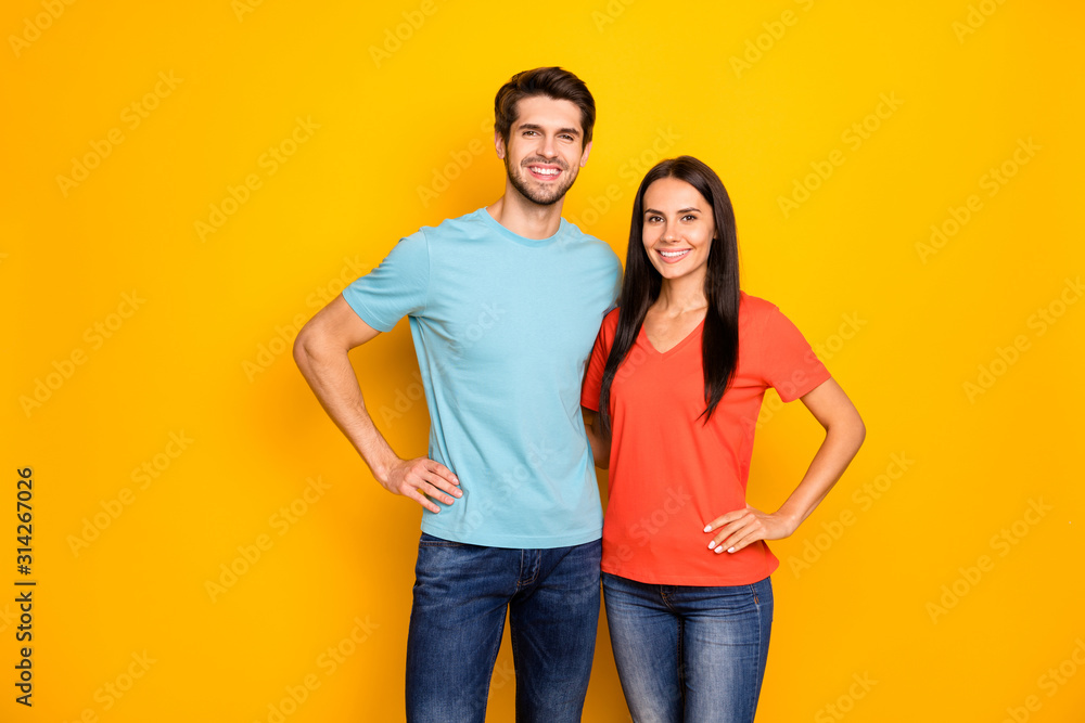 Photo of funny lovely two people couple guy and lady hugging hands by sides  one best team wear casual blue orange t-shirts jeans isolated over yellow  color background Stock Photo | Adobe