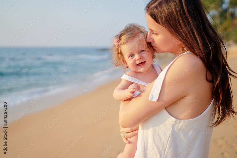 Portrait of happy young mother holding little daughter on the tropical beach. Portrait of happy young mother holding little daughter on the tropical beach.
