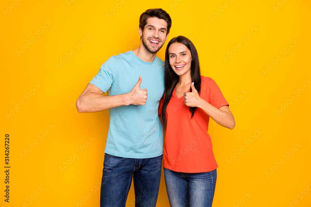 Photo of funny two people couple in love guy lady hugging raising thumb fingers expressing agreement wear casual blue orange t-shirts jeans isolated over yellow color background Photo of funny two people couple in love guy lady hugging raising thumb fingers expressing agreement wear casual blue orange t-shirts jeans isolated over yellow color background