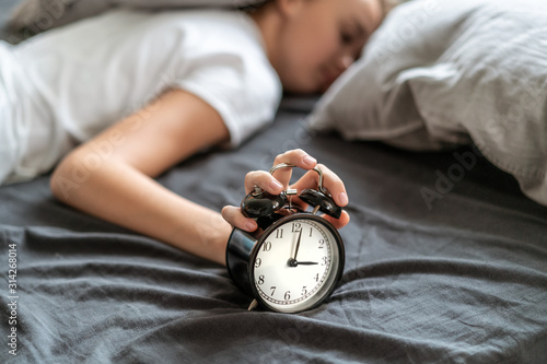 Fotografie Woman with insomnia lying in bed with her head under her pillow trying to sleep