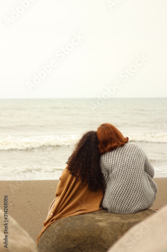 two women sitting in beach together