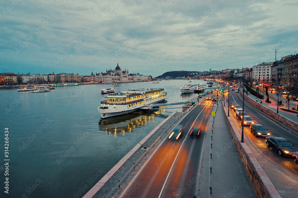 Danube River at blue hour twilight in city of Budapest, Hungary, Cruise and dinner boat near riverside promenade.