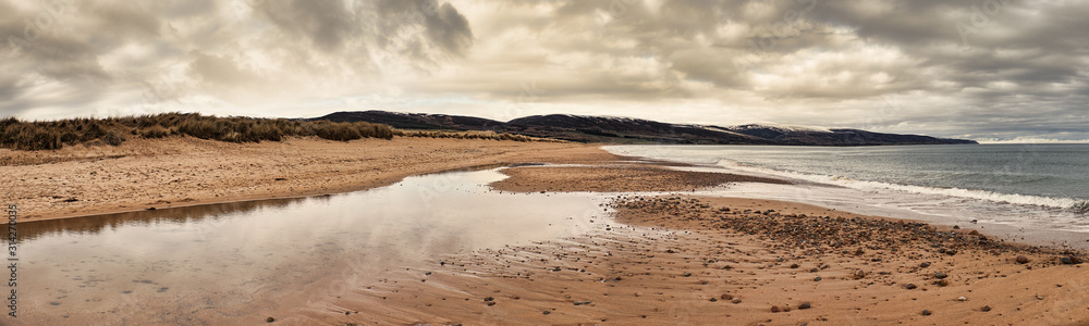 Dramatic winter clouds overshadowing Brora beach with snow on the hills Dramatic winter clouds overshadowing Brora beach with snow on the hills