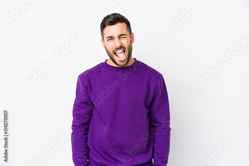 Young caucasian man against a white background isolated funny and friendly sticking out tongue.